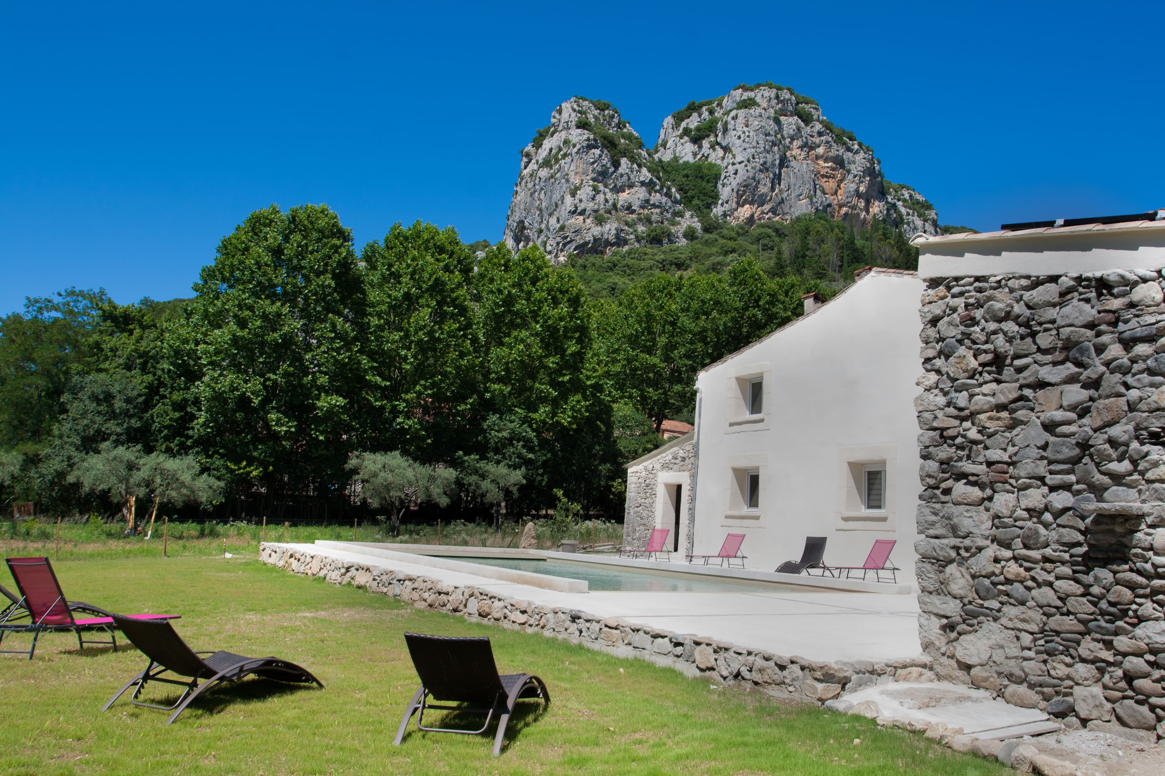 Les bâtiments en pierre du domaine et sa piscine, au pied de la falaise du Thaurac